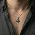 Load image into Gallery viewer, Polished silver serpent necklace with coiled knot design and detailed scale texture worn on the neck in a close lifestyle frame, highlighting the symmetrical snake motif and sculptural form