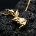 Load image into Gallery viewer, Gold plated origami bunny pendant with sharp geometric folds, minimalist rabbit shape, and contemporary sculptural form showcased on black volcanic rock in a refined macro jewelry image