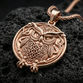 Load image into Gallery viewer, Rose gold plated owl necklace with sculpted feather relief, circular owl silhouette, and timeless wisdom-inspired design resting on volcanic rock in an elegant close-up product presentation