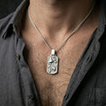Load image into Gallery viewer, Polished silver swordfish necklace with surrounding fish relief and rectangular silhouette worn on the neck in a close lifestyle frame, highlighting the underwater detailing and refined ocean motif