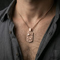 Load image into Gallery viewer, Rose gold plated swordfish necklace with sculpted marine scene, detailed fish relief, and refined rectangular form worn on the neck in a refined lifestyle shot with a warm and sophisticated presentation