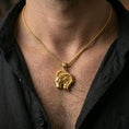 Load image into Gallery viewer, Gold plated Aries pendant with bold ram head motif and sweeping horn silhouette worn on the neck in a premium lifestyle composition with refined astrology jewelry styling