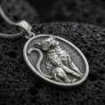 Load image into Gallery viewer, A 925 sterling silver cat pendant on black volcanic stone, with an oxidized finish highlighting the seated feline relief.