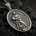 Load image into Gallery viewer, A 925 sterling silver Saint John the Evangelist oval medallion on black volcanic stone with oxidized depth and coin texture.