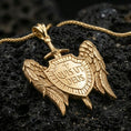 Load image into Gallery viewer, Gold plated Saint Michael medal pendant with detailed feathered wings, sword, and engraved shield resting on black volcanic rock in a dramatic macro product image