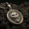 Load image into Gallery viewer, Bronze roaring gorilla pendant with fierce open-mouth ape relief, oval medallion frame, and bold primal animal silhouette displayed on dark volcanic rock in a close-up luxury jewelry composition