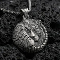 Load image into Gallery viewer, Oxidized tiger pendant with curled sleeping feline form, detailed stripe engraving, and round symbolic jungle silhouette displayed on dark volcanic rock in a close-up luxury jewelry composition