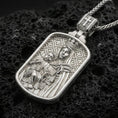 Load image into Gallery viewer, Polished silver religious pendant with Virgin Mary and infant Jesus design in a rounded rectangular frame placed on textured volcanic rock in a premium studio product shot
