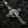 Load image into Gallery viewer, Oxidized crucifix pendant with INRI plaque, detailed Jesus figure, and ornate baroque cross design displayed on dark volcanic rock in a close-up luxury jewelry composition