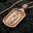 Load image into Gallery viewer, Rose gold plated religious Guadalupe pendant with Virgin Mary relief, radiant motif, and framed icon design resting on volcanic rock in an elegant close-up product presentation