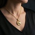 Load image into Gallery viewer, Gold plated lioness pendant with sculpted female lion relief, graceful profile silhouette, and symbolic animal design worn on the neck in a premium lifestyle composition with elegant wildlife jewelry styling