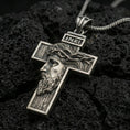 Load image into Gallery viewer, Oxidized Jesus cross pendant with side profile portrait, crown of thorns, and INRI detail displayed on dark volcanic rock in a close-up luxury jewelry composition