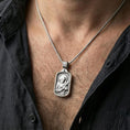 Load image into Gallery viewer, Polished silver Saint Francis medallion worn on the neck in a close lifestyle frame, highlighting the detailed saint portrait and sacred symbolism
