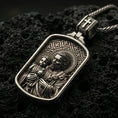 Load image into Gallery viewer, Oxidized Saint Joseph pendant with Child Jesus, halo details, and framed devotional portrait displayed on dark volcanic rock in a close-up luxury jewelry composition