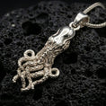 Load image into Gallery viewer, Polished silver octopus pendant necklace displayed on black volcanic rock, shown in a refined macro product shot with flowing tentacle details.