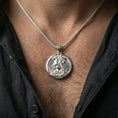 Load image into Gallery viewer, Polished silver Saint George medallion with horseman relief worn on the neck in a close lifestyle frame, highlighting the detailed saint figure and circular devotional design