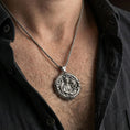 Load image into Gallery viewer, Oxidized Saint Raphael pendant with winged archangel and healing staff worn on the neck in a lifestyle jewelry shot, styled against the chest for a bold and spiritual look