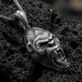 Load image into Gallery viewer, Sterling silver gorilla head pendant necklace with an oxidized finish resting on textured volcanic rock, captured in a close-up premium studio composition.