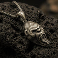 Load image into Gallery viewer, Bronze gorilla head pendant necklace with an oxidized finish resting on textured volcanic rock, captured in a close-up premium studio composition.
