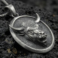 Load image into Gallery viewer, Sterling silver bull pendant necklace with an oxidized finish resting on textured volcanic rock, captured in a close-up premium studio composition.