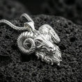 Load image into Gallery viewer, Polished silver ram head pendant necklace displayed on black volcanic rock, shown in a refined macro product shot with detailed horn and facial sculpting.