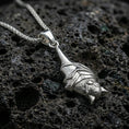 Load image into Gallery viewer, Polished silver hanging bat pendant necklace displayed on black volcanic rock, shown in a refined macro product shot with detailed wing wrap and sculpted bat face.