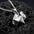 Load image into Gallery viewer, Polished silver origami camel pendant necklace displayed on black volcanic rock, shown in a refined macro product shot with crisp folded geometric detail.