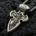 Load image into Gallery viewer, Oxidized Saint Michael cross pendant with winged archangel figure, engraved Cyrillic inscription, and elongated gothic silhouette displayed on dark volcanic rock in a close-up luxury jewelry composition