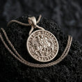 Load image into Gallery viewer, Polished silver Knights Templar seal pendant necklace displayed on black volcanic rock, shown in a refined macro product shot with engraved medieval lettering and mounted knight detail.
