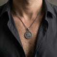 Load image into Gallery viewer, Oxidized Knights Templar seal pendant necklace worn on the neck, styled in a dark lifestyle portrait with an open shirt and masculine presentation.