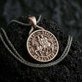 Load image into Gallery viewer, Bronze Knights Templar seal pendant necklace with an oxidized finish resting on textured volcanic rock, captured in a close-up premium studio composition.