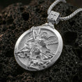 Load image into Gallery viewer, Polished silver Saint Michael pendant necklace displayed on black volcanic rock, shown in a refined macro product shot with detailed archangel relief and symbolic battle scene.