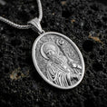 Load image into Gallery viewer, Polished silver Saint Patrick pendant necklace displayed on black volcanic rock, shown in a refined macro product shot with detailed bishop figure and pastoral staff relief.
