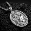 Load image into Gallery viewer, Polished silver Saint Sebastian pendant necklace displayed on black volcanic rock, shown in a refined macro product shot with detailed martyr figure relief.