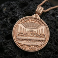 Load image into Gallery viewer, Rose gold plated two-sided Christian pendant with circular Last Supper design on one side and Lord’s Prayer inscription on the reverse resting on volcanic rock in an elegant close-up product presentation