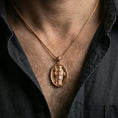 Load image into Gallery viewer, Rose gold plated Saint Dominic pendant with halo detail and devotional portrait worn on the neck in a refined lifestyle shot with a warm and elegant presentation