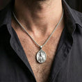 Load image into Gallery viewer, Polished silver Saint Jude medal with sacred portrait relief worn on the neck in a close lifestyle frame, highlighting the oval silhouette and refined saint detail