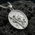 Load image into Gallery viewer, Polished silver Saint Christopher medal with detailed saint relief, Child Jesus figure, and engraved devotional lettering placed on textured volcanic rock in a premium studio product shot