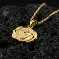 Load image into Gallery viewer, Gold plated third eye chakra pendant with sacred Om motif, symbolic triangular center, and smooth spiritual silhouette showcased on black volcanic rock in a refined macro jewelry image