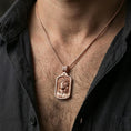 Load image into Gallery viewer, Rose gold plated religious Jesus pendant with framed sacred portrait and crown of thorns worn on the neck in a refined lifestyle shot with a warm and elegant presentation