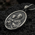 Load image into Gallery viewer, Oxidized Saint Joseph pendant with Child Jesus, halo details, and oval devotional portrait displayed on dark volcanic rock in a close-up luxury jewelry composition