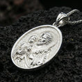 Load image into Gallery viewer, Polished silver Saint Joseph medallion with Child Jesus, sacred halo relief, and detailed oval frame placed on textured volcanic rock in a premium studio product shot