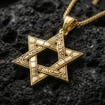 Load image into Gallery viewer, Gold plated Star of David pendant with geometric hexagram form, engraved ornamental patterning, and open center showcased on black volcanic rock in a refined macro jewelry image