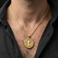 Load image into Gallery viewer, Gold plated Saint Benedict pendant with haloed saint figure and round devotional form worn on the neck in a premium lifestyle composition with classic Christian jewelry styling