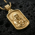 Load image into Gallery viewer, Gold plated Virgin Mary pendant with Baby Jesus motif, ornate devotional detailing, and rounded rectangular religious form showcased on black volcanic rock in a refined macro jewelry image