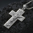Load image into Gallery viewer, Polished silver Jesus Ascension cross pendant necklace displayed on black volcanic rock, shown in a refined macro product shot with detailed sacred figure and radiant cross relief.