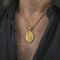 Load image into Gallery viewer, Gold plated Saint Hubert pendant necklace worn on the neck, captured on a human model in a premium dark-toned lifestyle frame.
