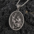 Load image into Gallery viewer, Sterling silver Saint Hubert pendant necklace with an oxidized finish resting on textured volcanic rock, captured in a close-up premium studio composition.
