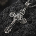 Load image into Gallery viewer, Sterling silver Saint Benedict crucifix necklace with an oxidized finish resting on textured volcanic rock, captured in a close-up premium studio composition.