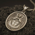 Load image into Gallery viewer, Bronze Saint Michael Archangel pendant necklace with an oxidized finish resting on textured volcanic rock, captured in a close-up premium studio composition.